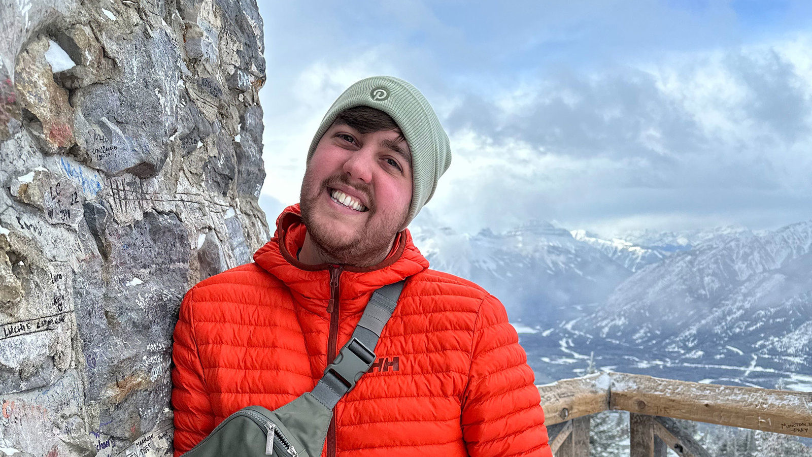 a man standing next to a rock wall