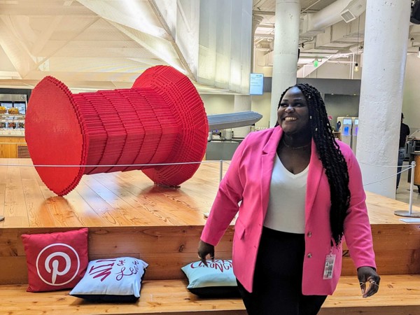 a person in pink jacket standing in front of a large red spool