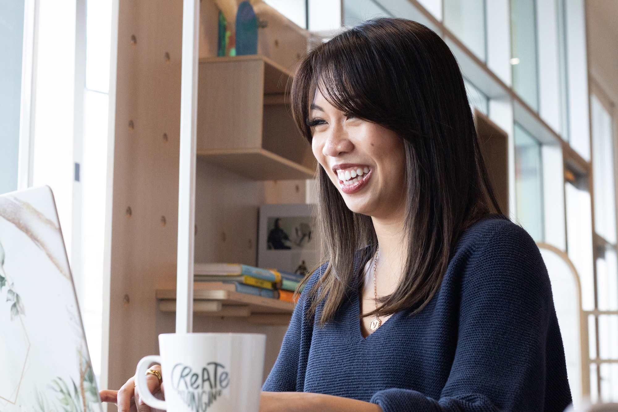 a woman smiling at a coffee cup
