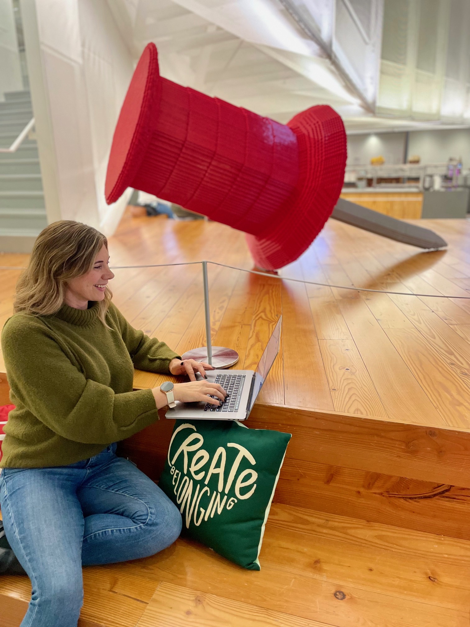 a woman sitting on a wood floor using a laptop