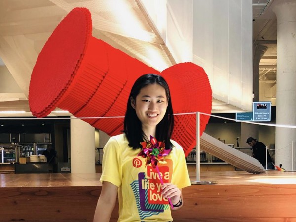 a woman smiling in front of a large red object