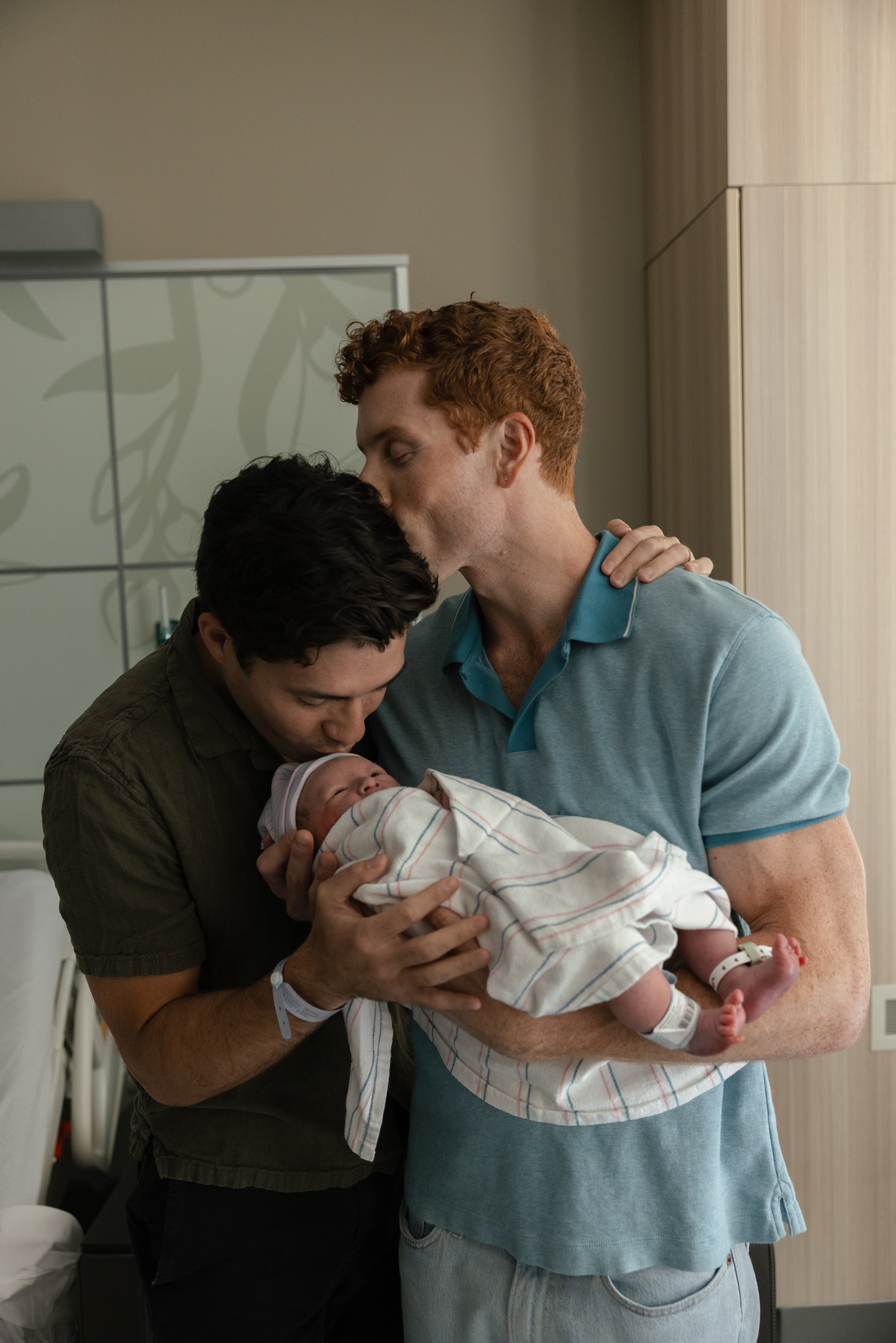 two men kissing a baby