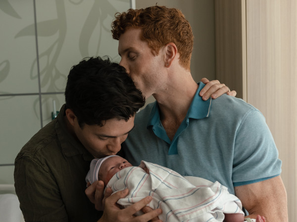 two men kissing a baby