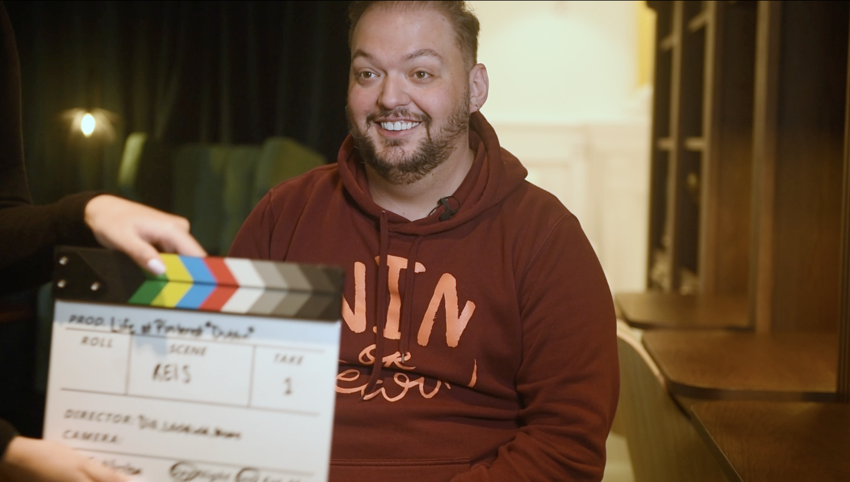 a person sitting in front of a movie clapper board