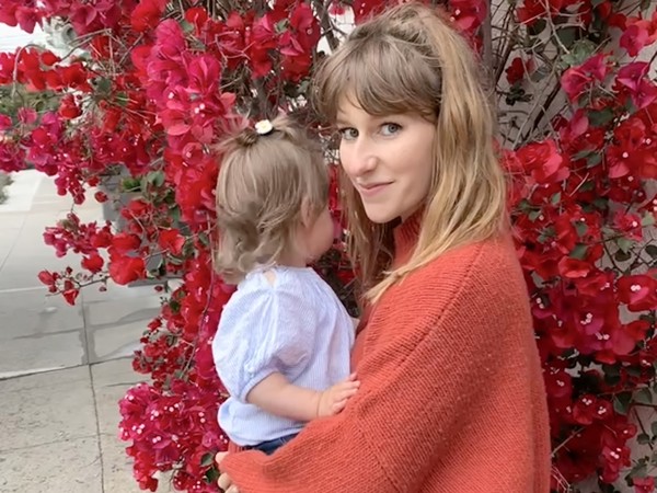 a person holding a child in front of a tree with red flowers