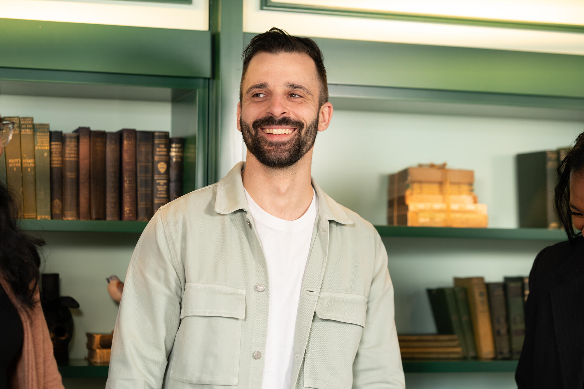 a man smiling in front of a shelf