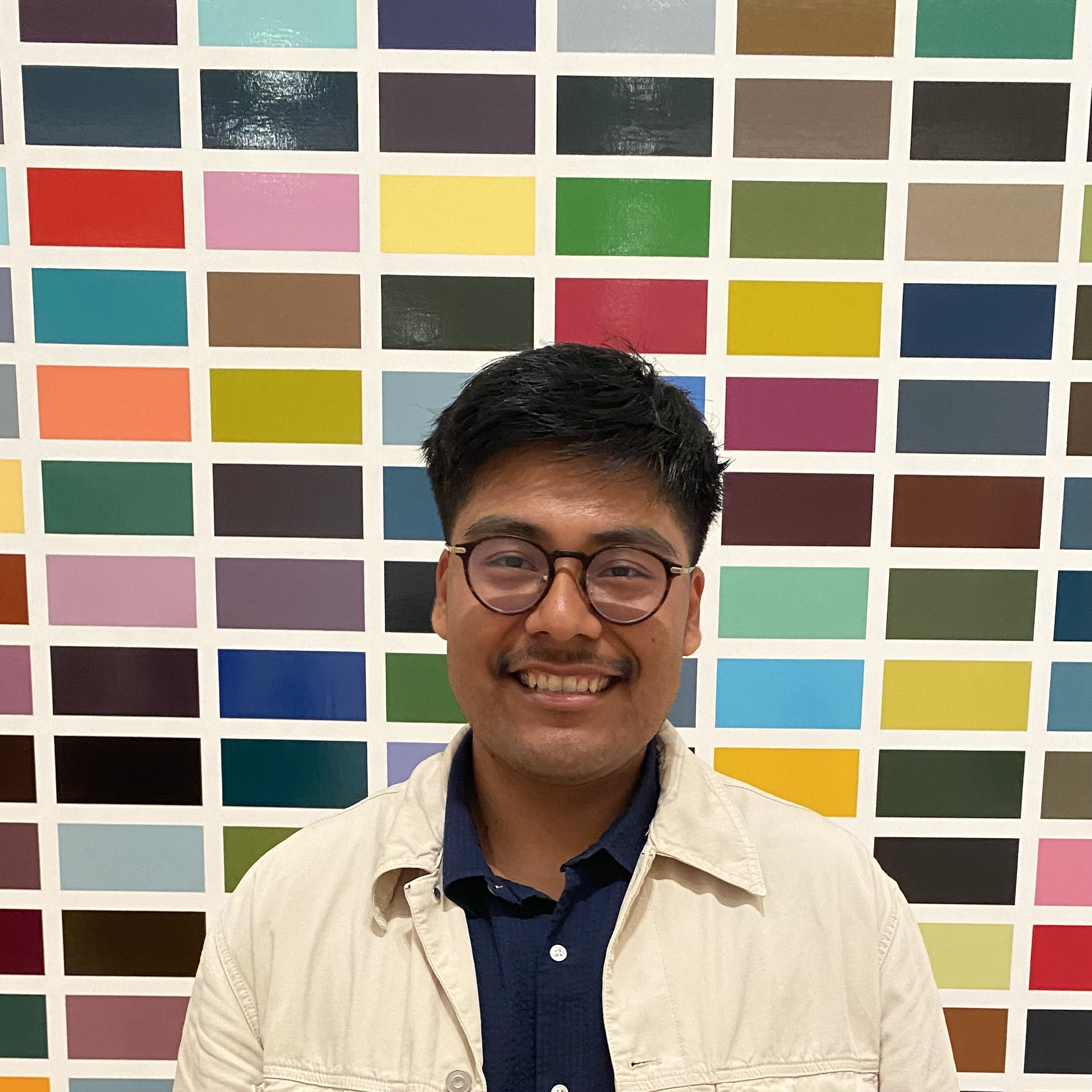 a person smiling in front of a wall of colorful squares