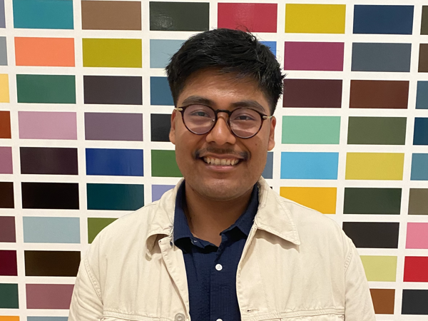 a person smiling in front of a wall of colorful squares
