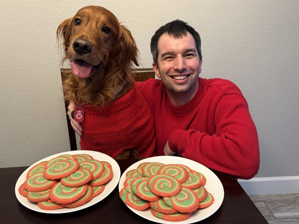a person and dog sitting at a table with cookies