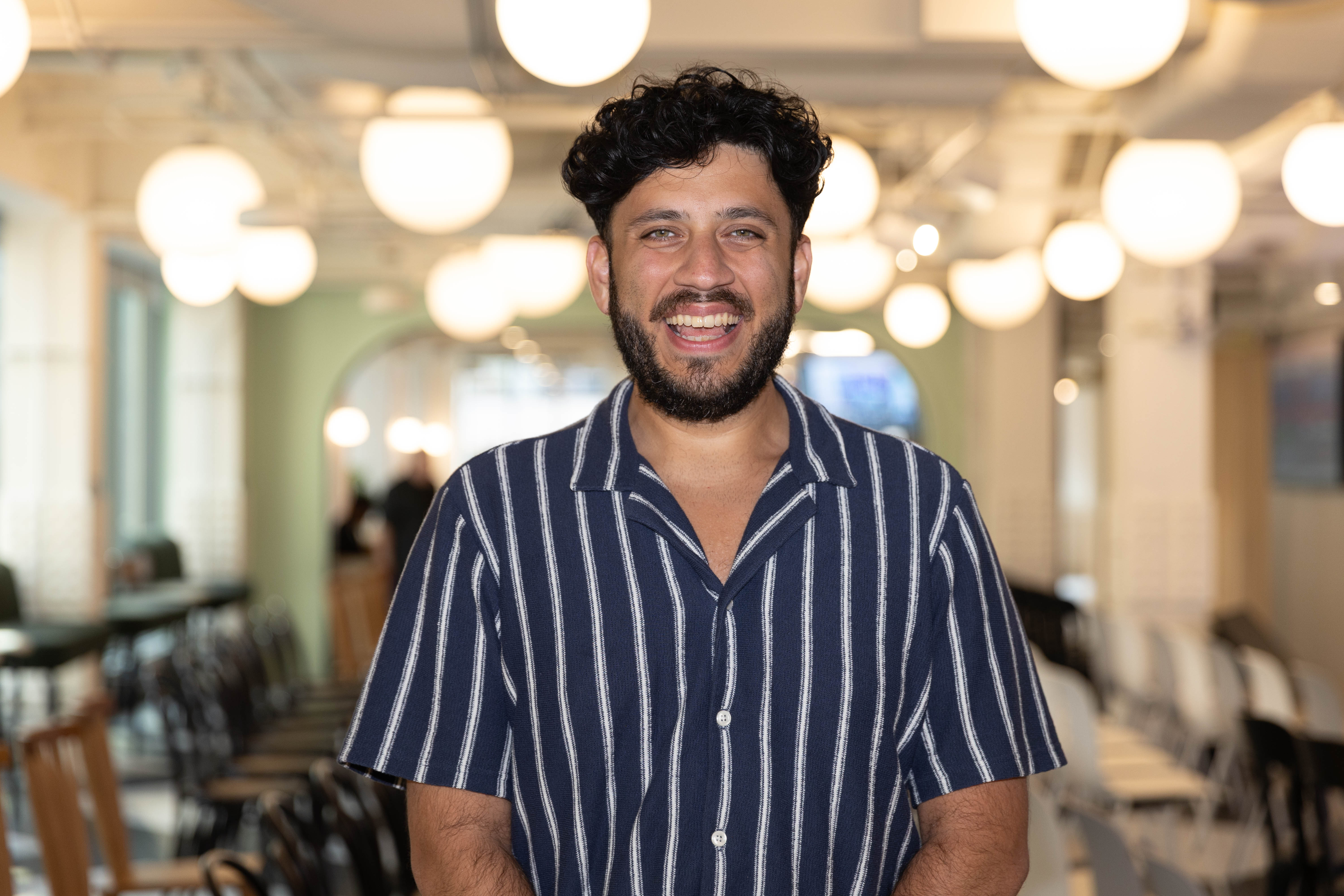 a person smiling in a room with chairs and lights