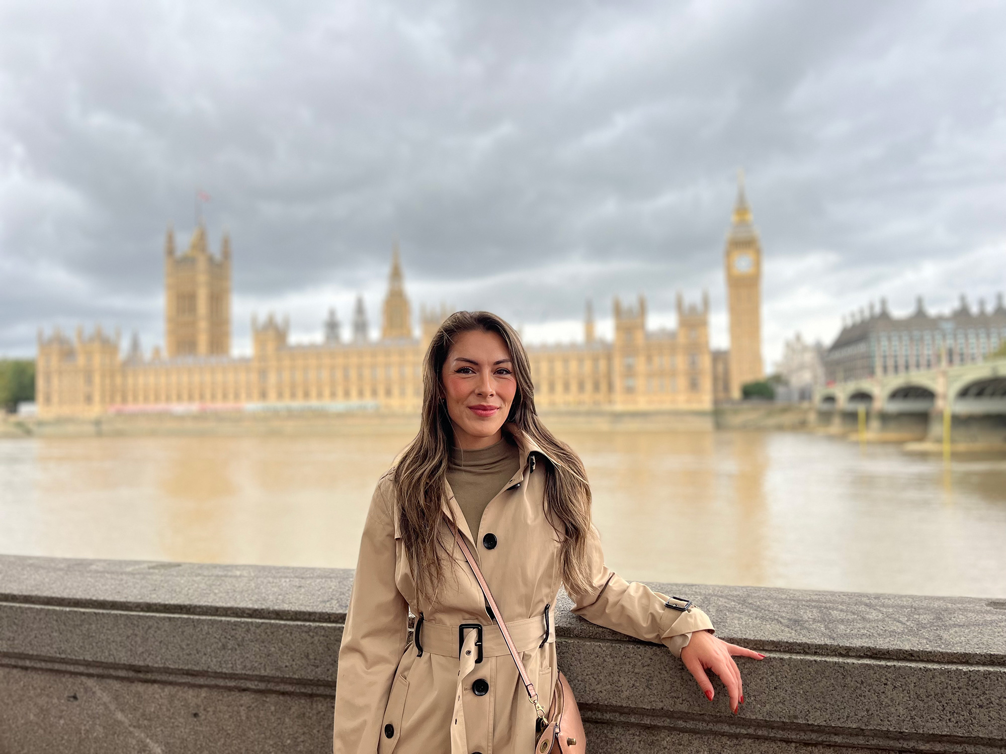 a woman standing on a stone ledge in front of a large building