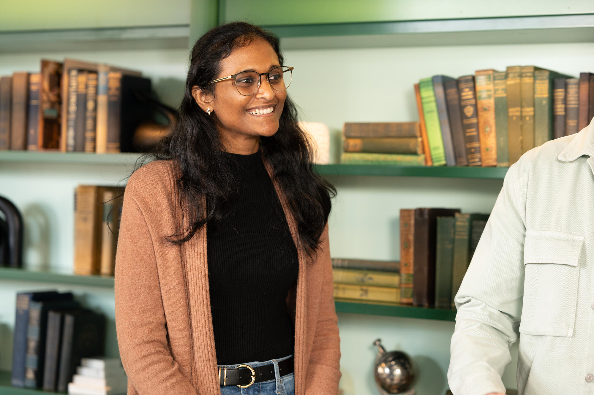 a woman smiling in front of a book shelf