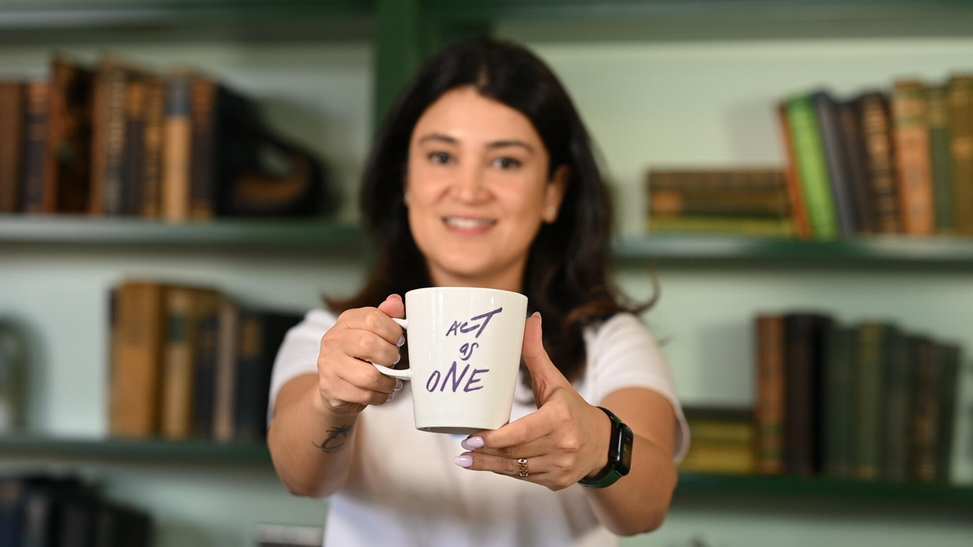 a person holding a white mug with writing on it