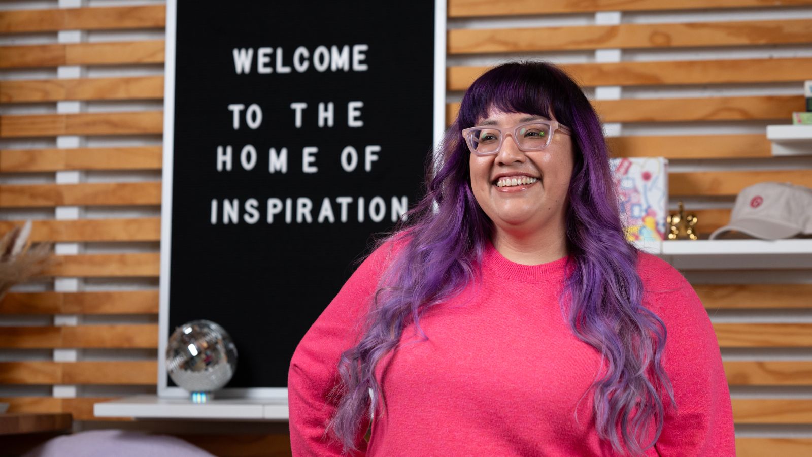 a person with purple hair and glasses smiling