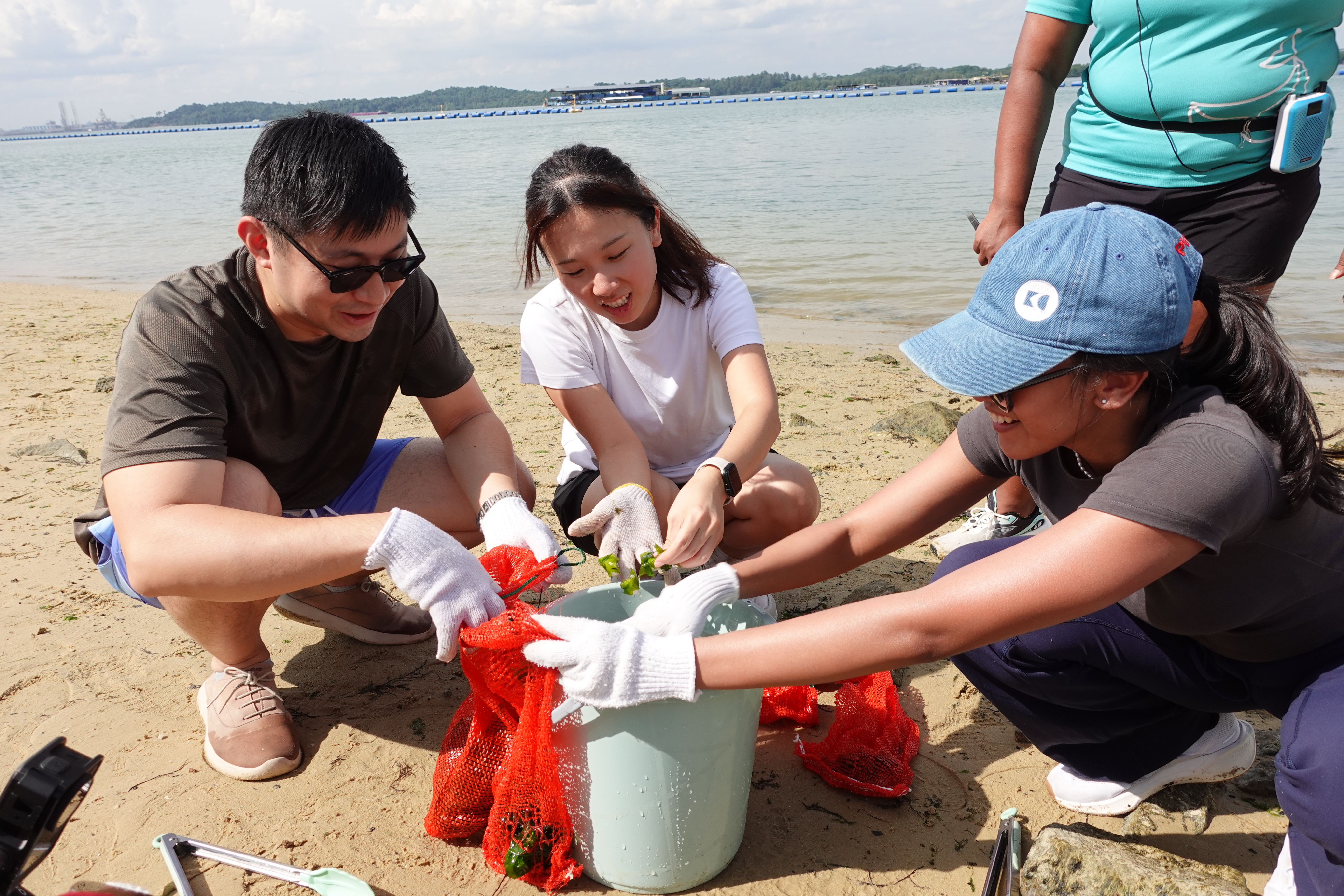 a group of people cleaning up a bucket on a beach