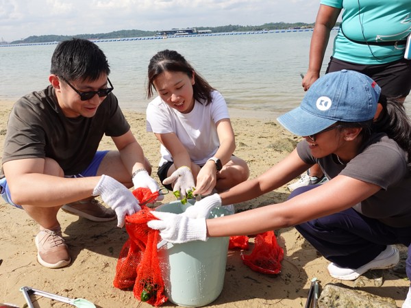 a group of people cleaning up a bucket on a beach