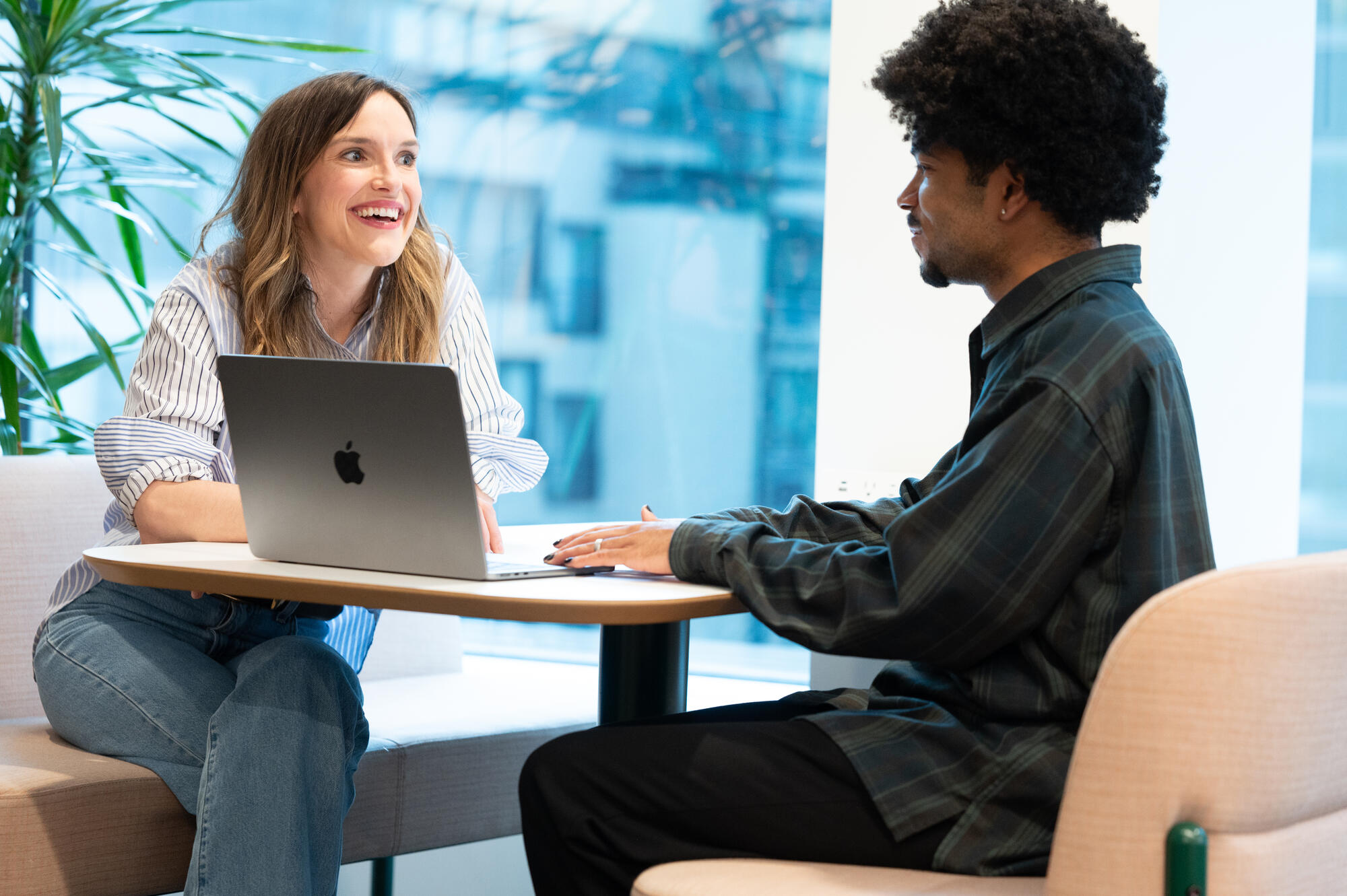 a person and person sitting at a table with a laptop