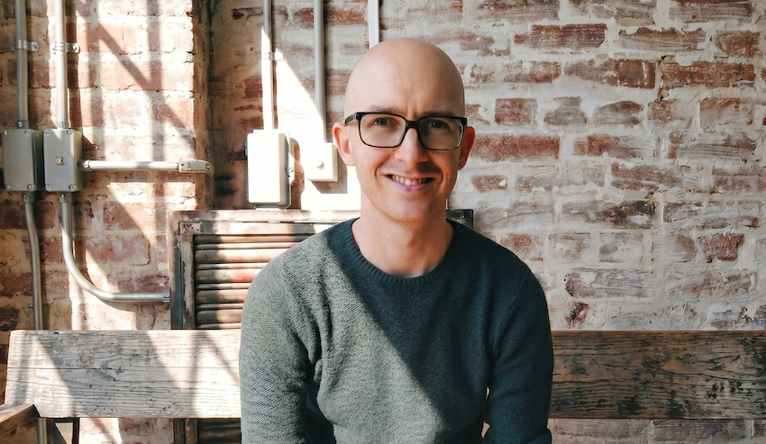 a person wearing glasses and a grey sweater