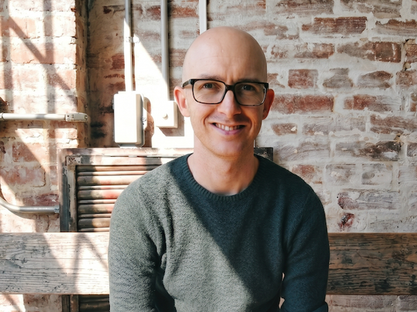 a person wearing glasses and a grey sweater