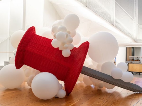a large red and grey object surrounded by white balloons