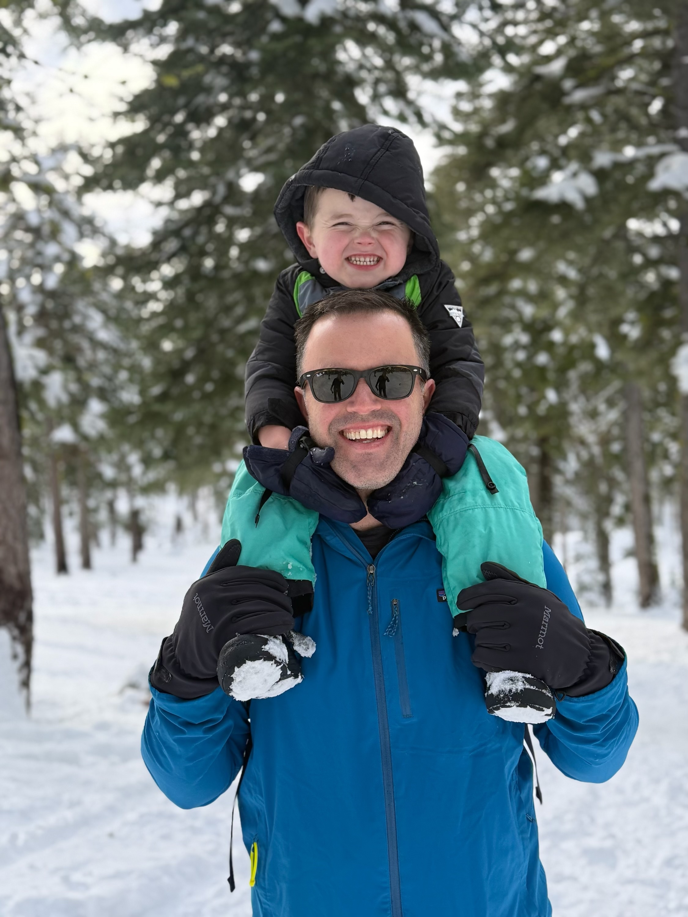 a person carrying a child on his shoulders in the snow