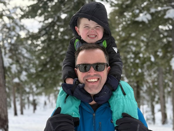 a person carrying a child on his shoulders in the snow