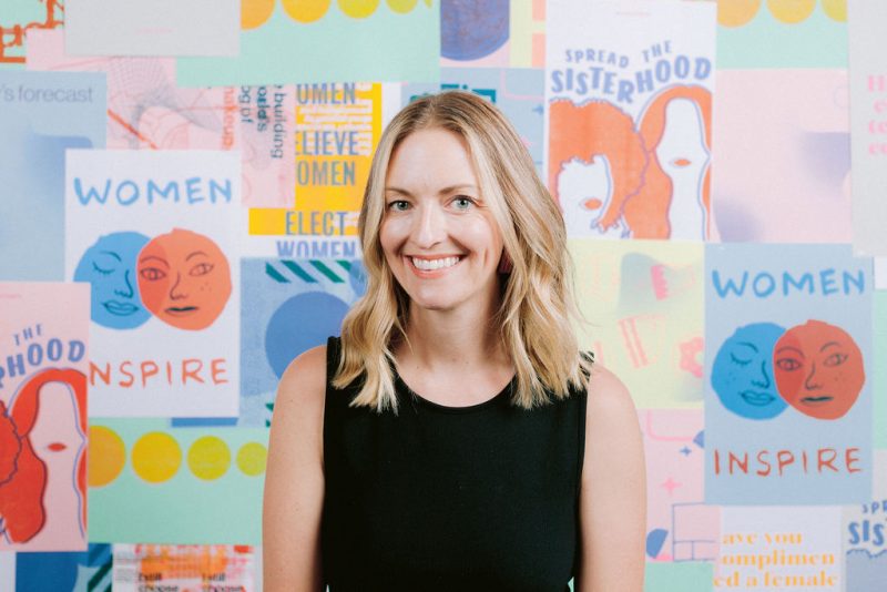 a woman smiling in front of a colorful wall