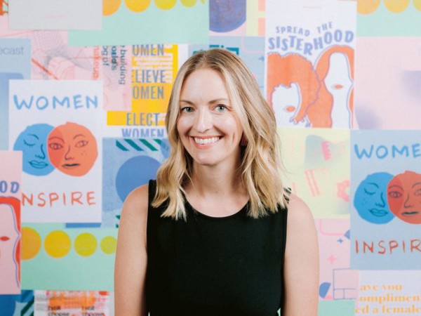 a woman smiling in front of a colorful wall