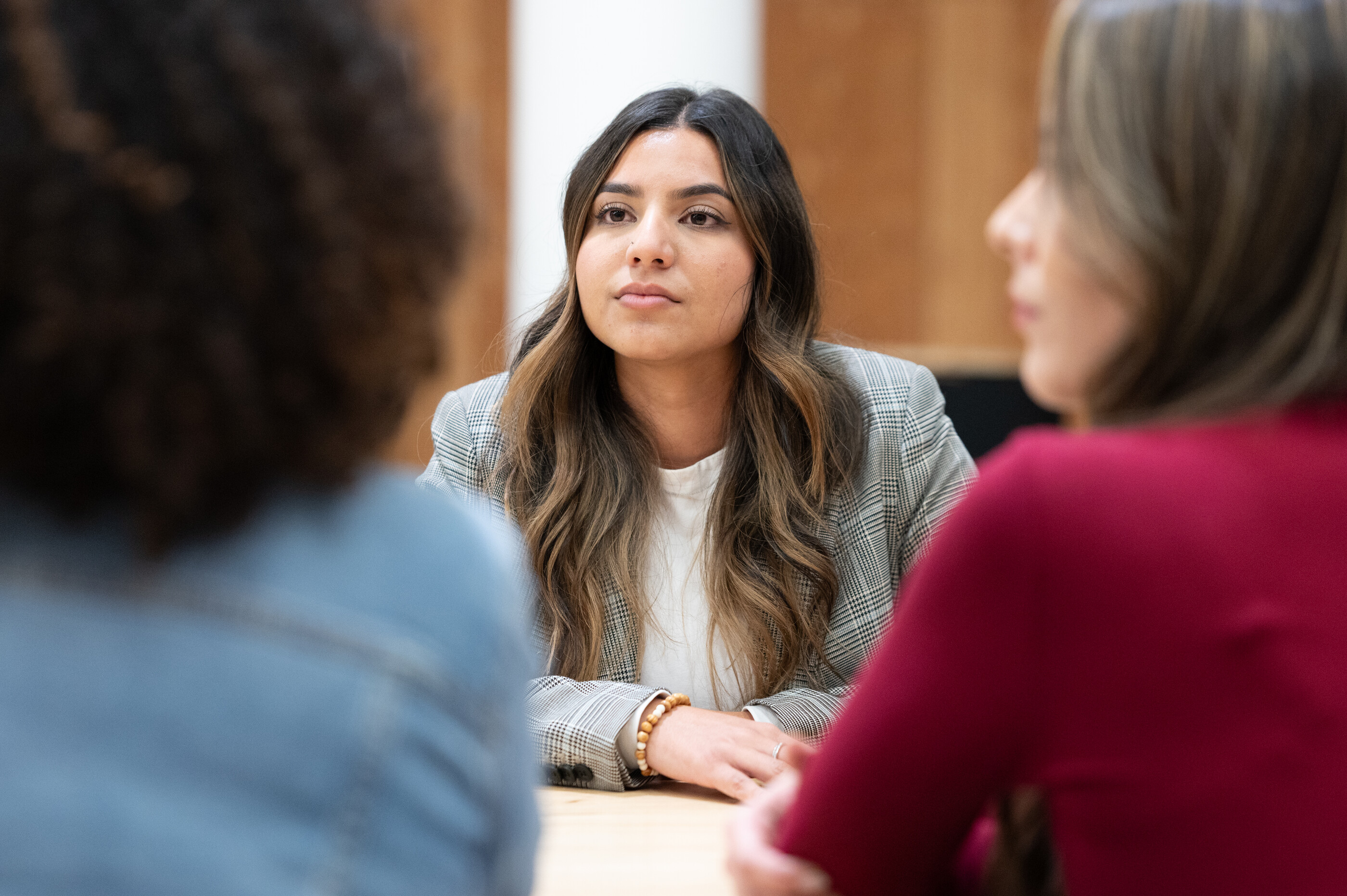 a woman sitting at a table with other people in the background