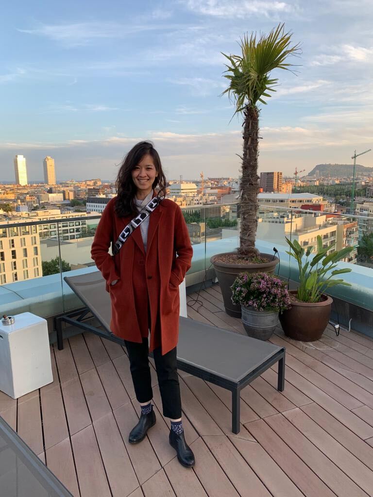 a person standing on a deck with a palm tree and a city in the background