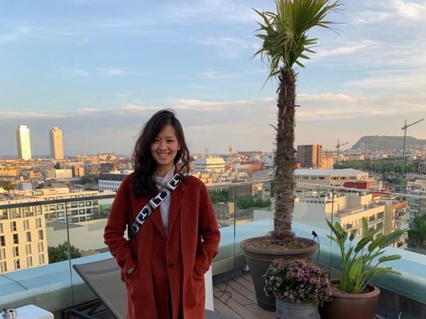 a person standing on a deck with a palm tree and a city in the background